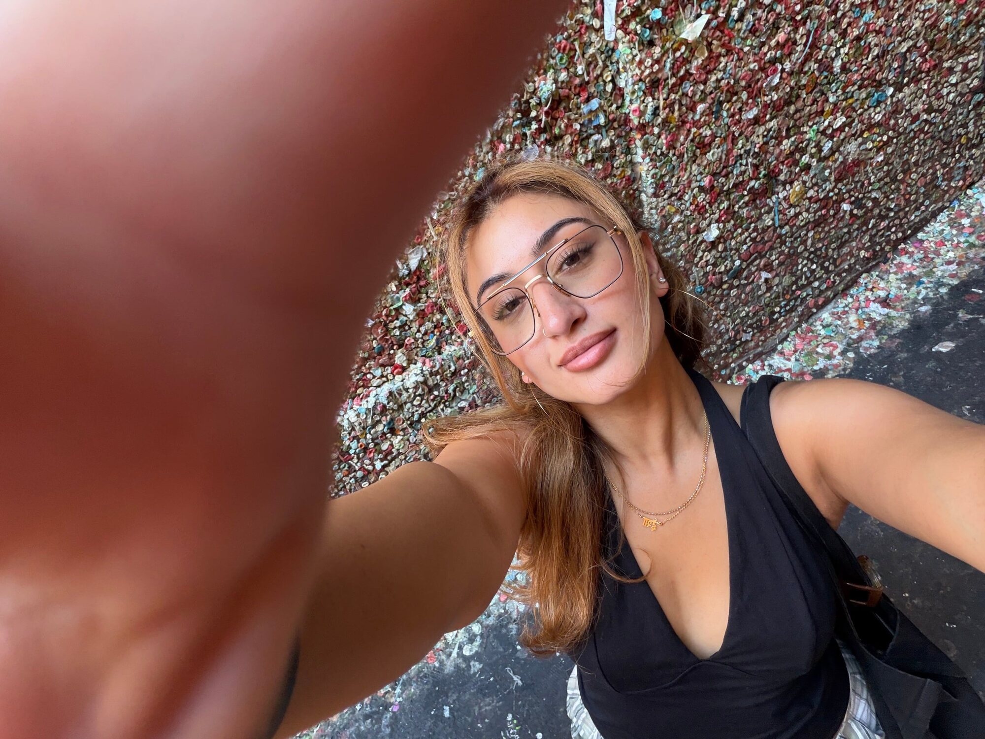 Isha Bhatt taking a selfie in front of a wall covered in chewing gum