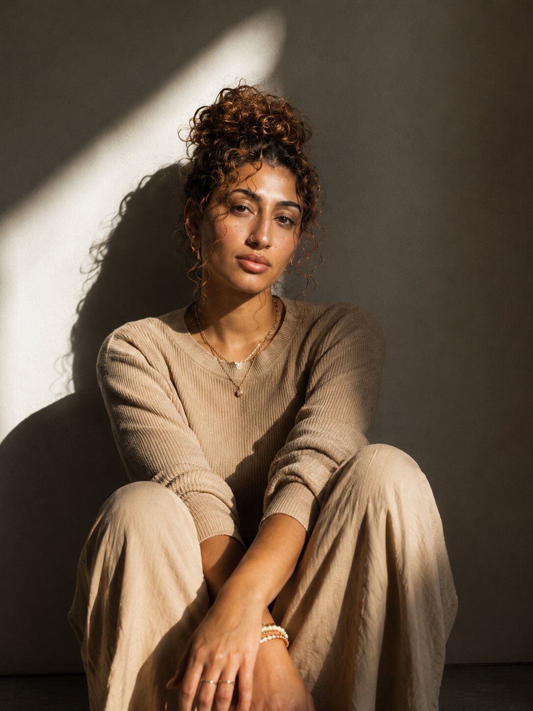 A woman sitting against a wall in a shaft of sunlight