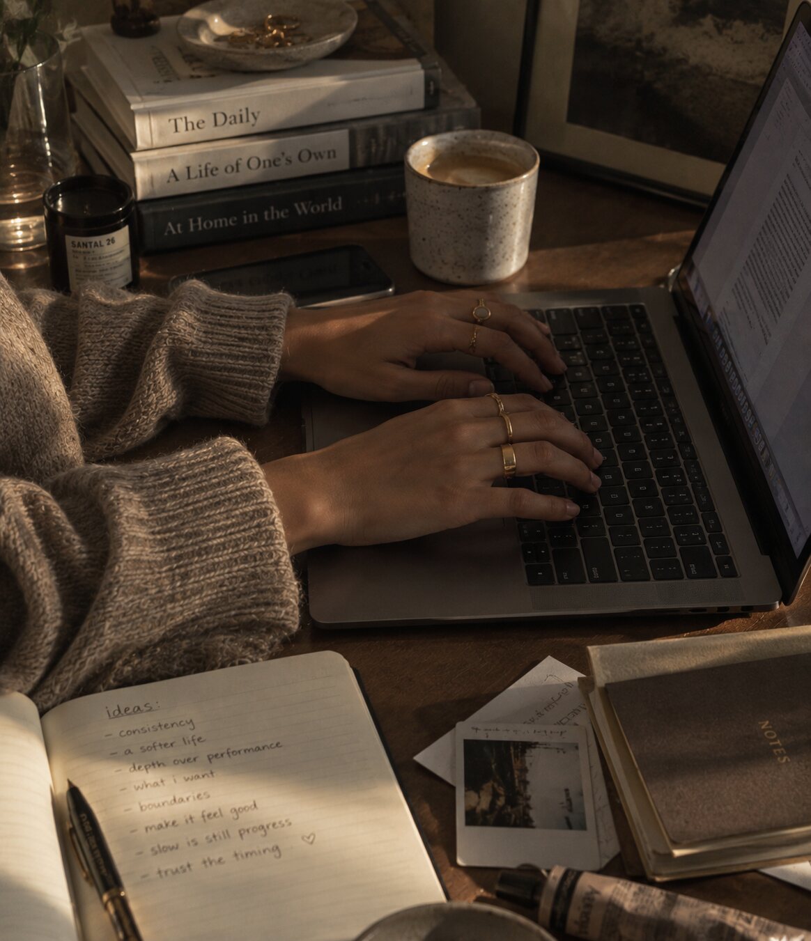 Hands typing on a laptop beside a mug